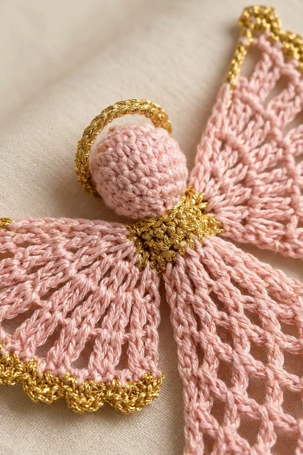 Handmade pink and gold tassel ornaments with crocheted spheres and metallic thread details on cream fabric.