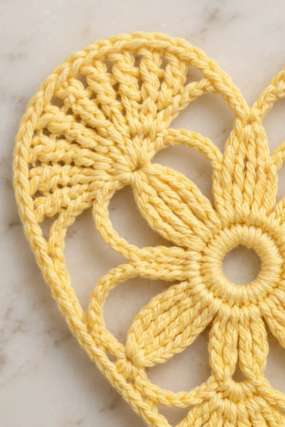Close-up of twisted yellow rope creating decorative knots and loops against a light marble background.