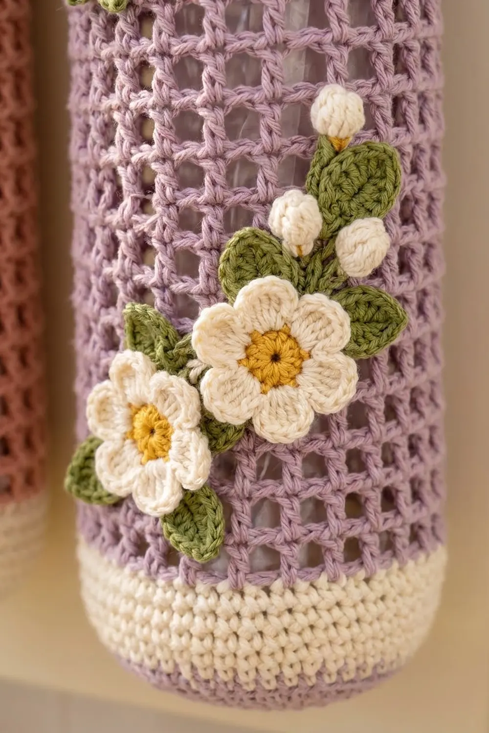 Crocheted white daisies with yellow centers attached to a lavender openwork sweater with cream ribbed cuff.