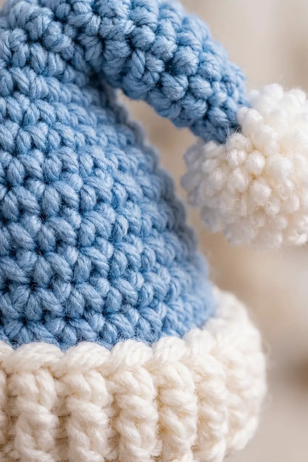 Close-up of a crocheted amigurumi toy featuring blue yarn body with white fluffy pom-pom details.