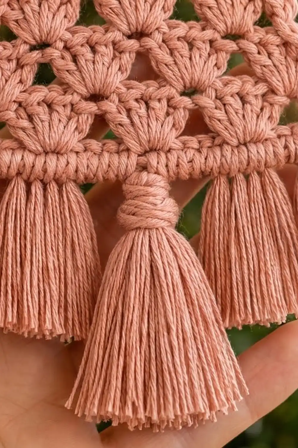 Close-up of dusty rose macramé trim with knotted nodes and hanging tassel fringe detail.