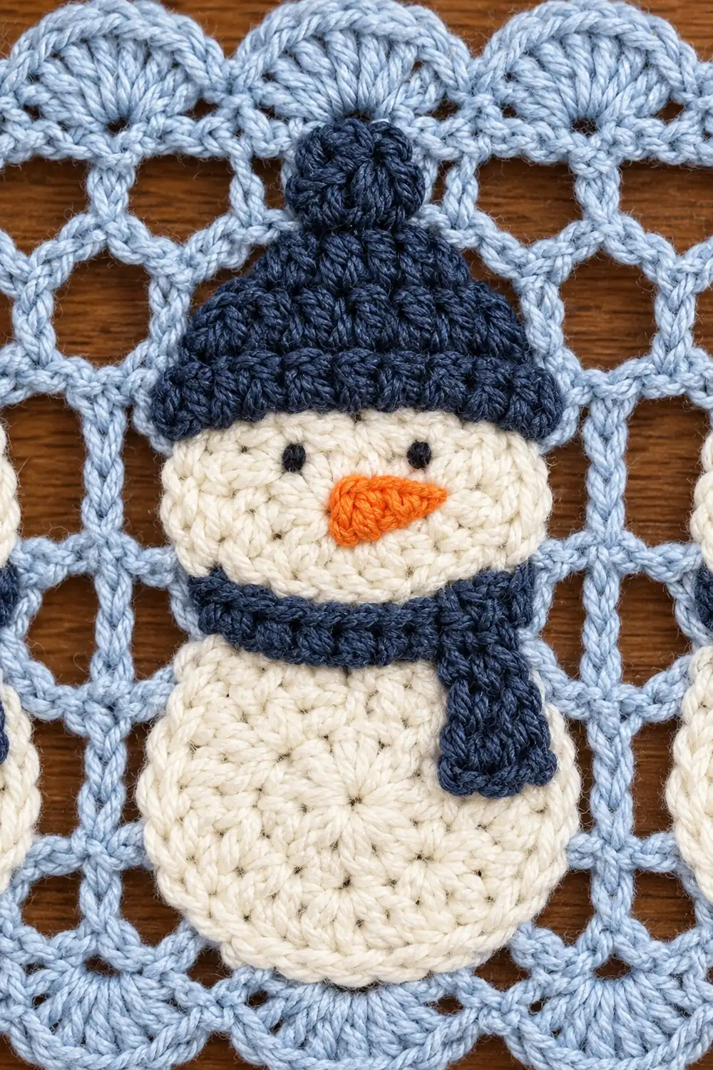 Crocheted snowman appliqué with dark blue hat and scarf on light blue quilted background.