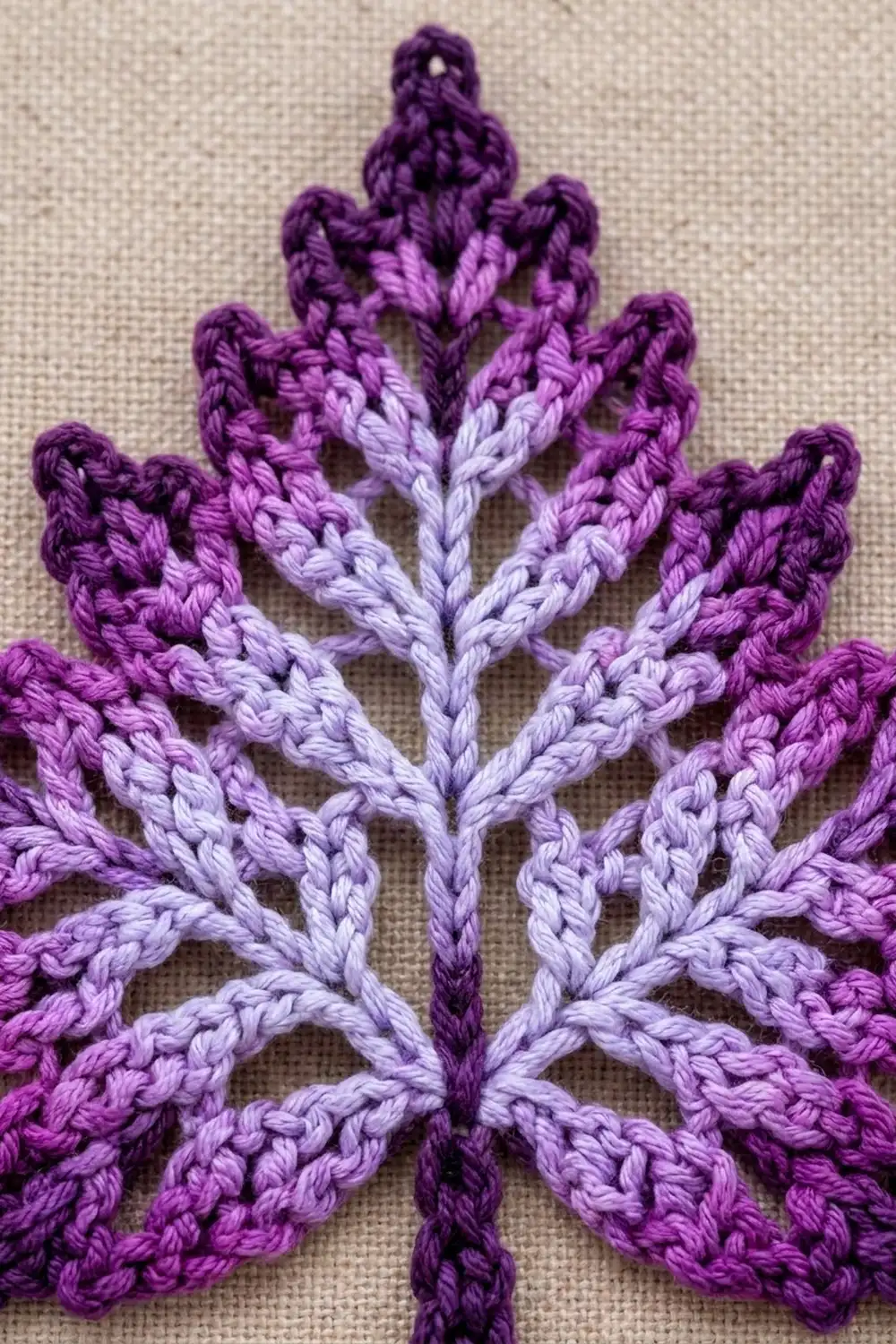 Embroidered purple and lavender leaf design with braided texture on beige linen fabric background.