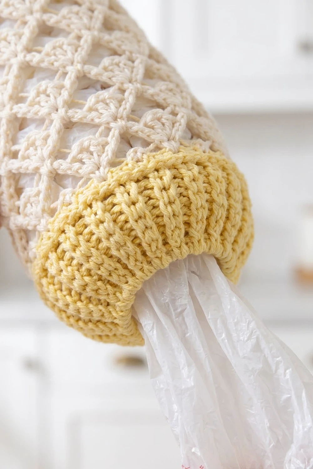 Close-up of crocheted dishcloths in cream and yellow colors draped over a white plastic bag.
