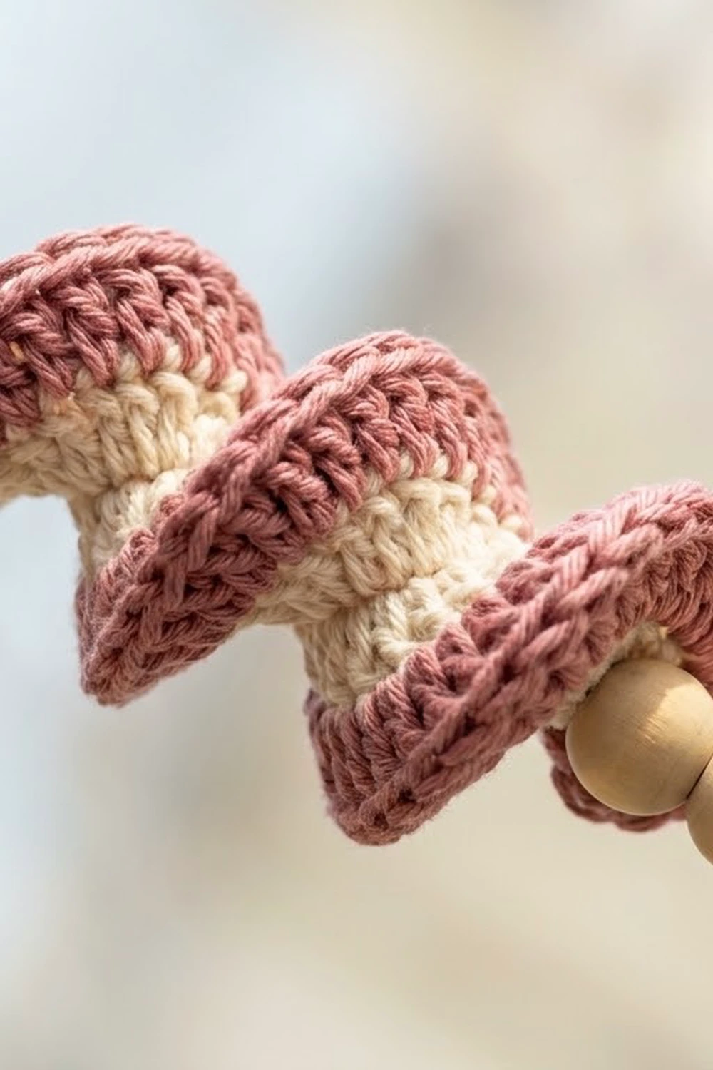 Crocheted pink and cream decorative ornaments with textured wings attached to a wooden ring.