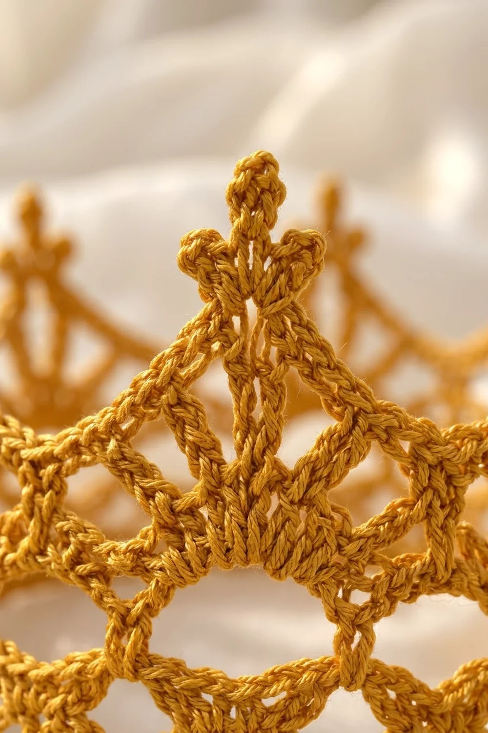 Golden crochet star motif with intricately twisted rope-like stitches against a soft, blurred neutral background.