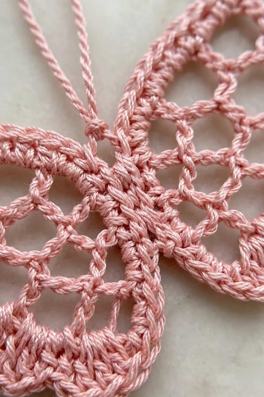 Pink crochet featuring open geometric lattice pattern with textured rope-twisted edges.