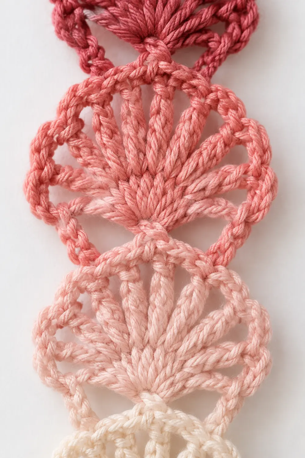 A gradient macramé wall hanging in pink and cream tones displaying intricate knotted rope patterns.