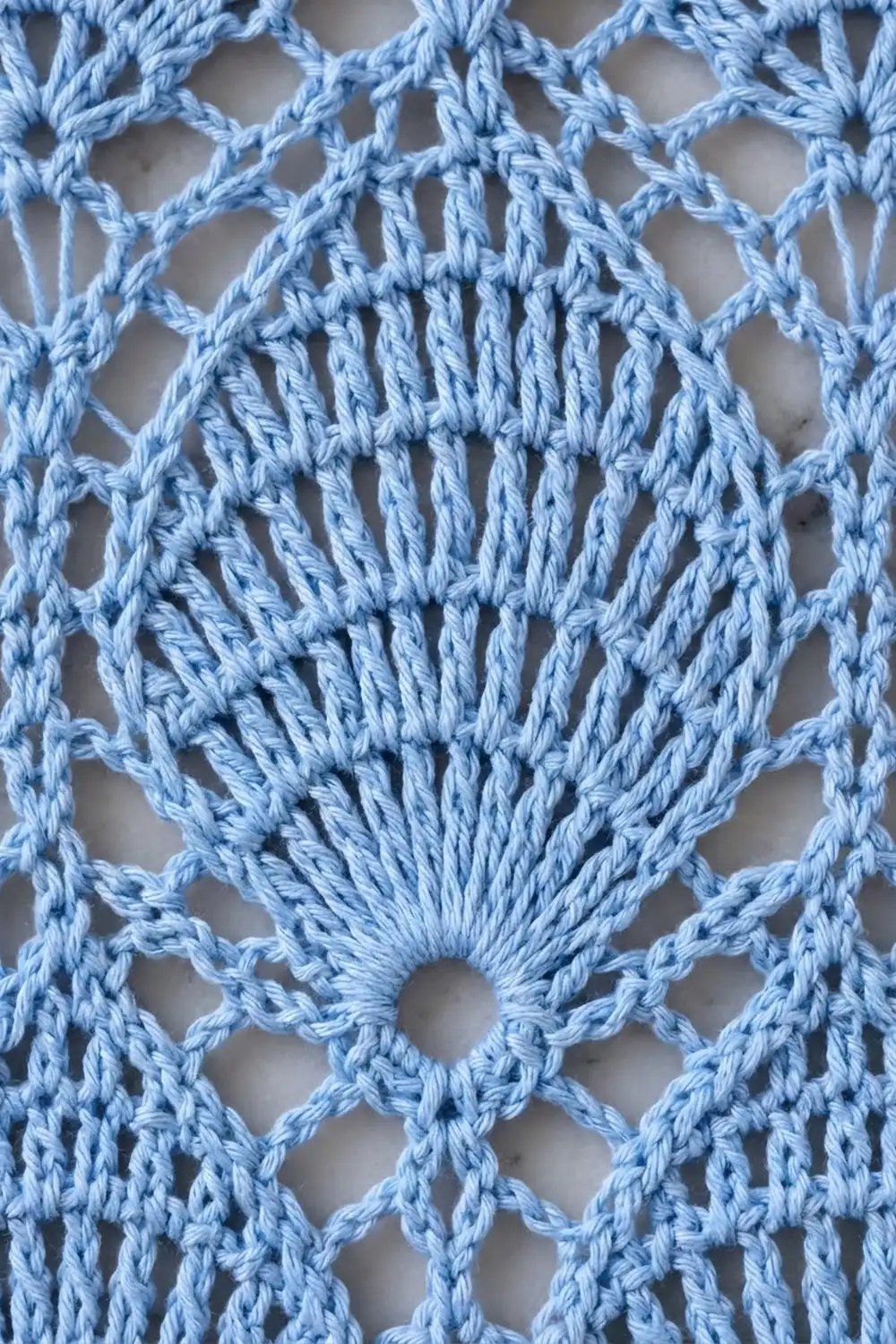 Light blue crochet lace featuring geometric diamond-shaped openwork and a densely stitched central medallion motif.