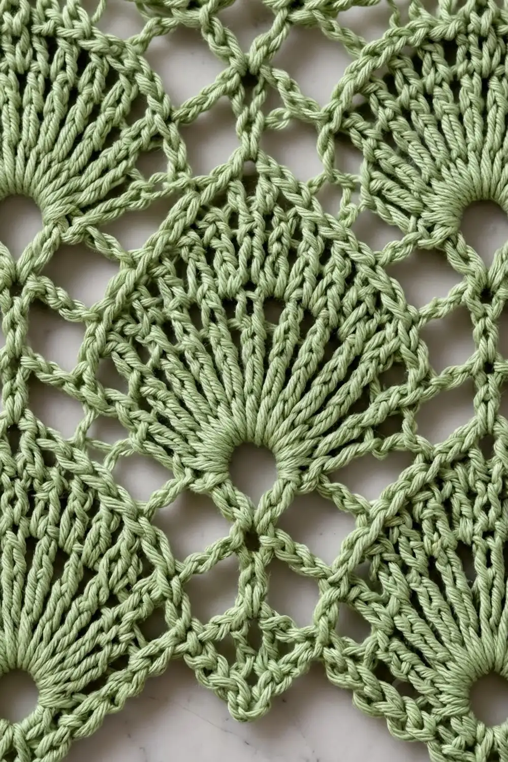 Sage green crocheted lace featuring detailed shell stitches and geometric open spaces in pattern.