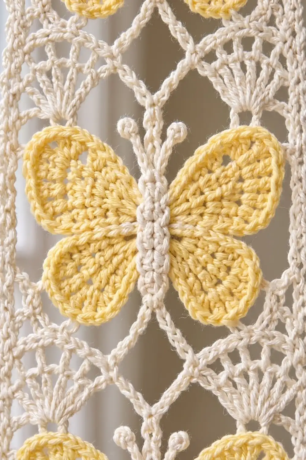 Close-up of a yellow crochet butterfly motif on cream-colored open lattice crochet fabric.