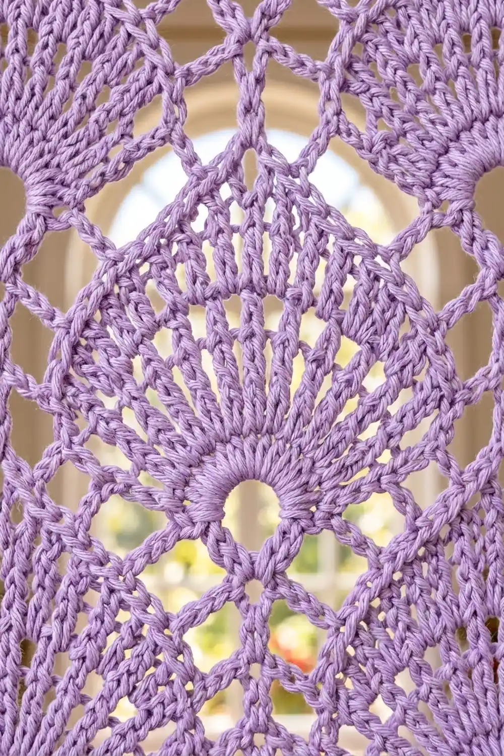 Lavender crochet lace with intricate openwork pattern and geometric diamond motifs, photographed against a softly blurred garden background.