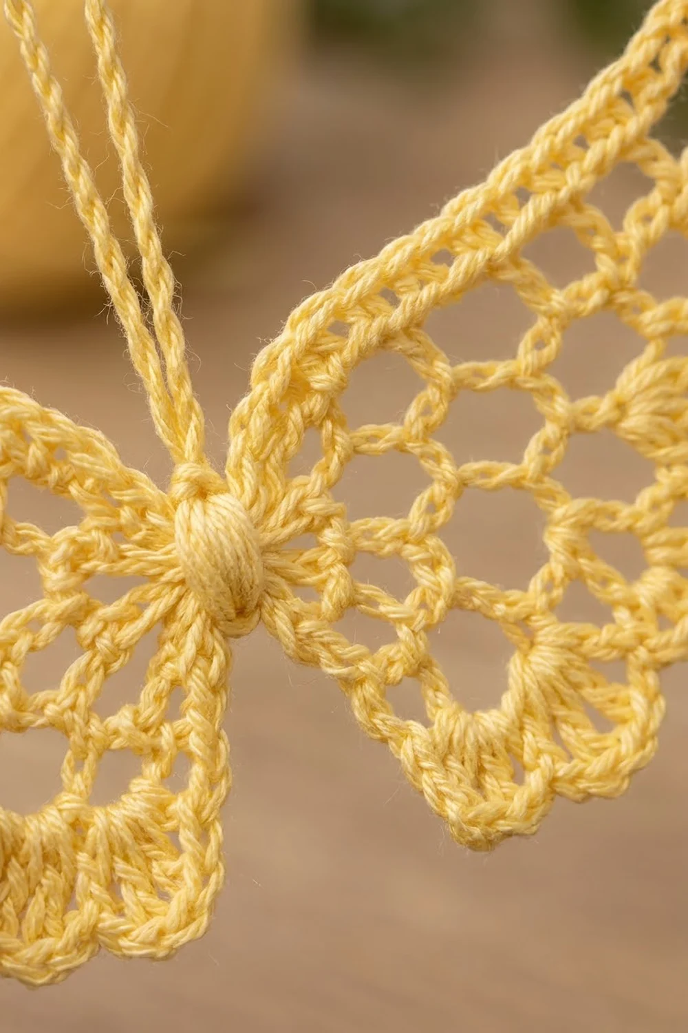 Intricately crocheted golden yellow lace with openwork knots and twisted strands displayed in close-up detail.