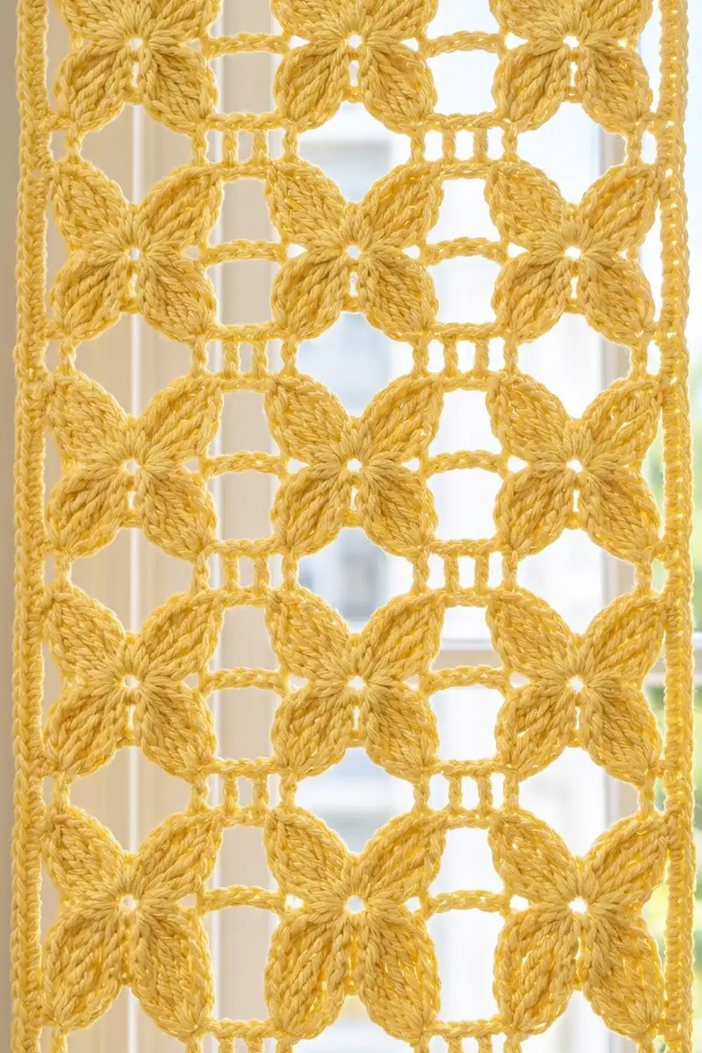 Mustard-yellow crocheted lace featuring repeating four-petal flower motifs with open square centers and connecting chains.