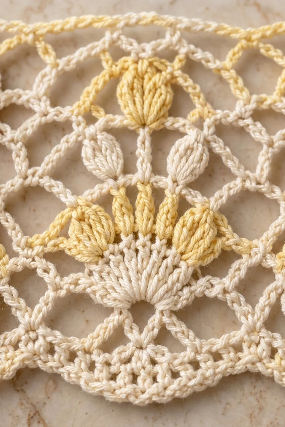 Close-up of cream and golden crocheted textile showing twisted rope yarn forming a geometric diamond lattice.
