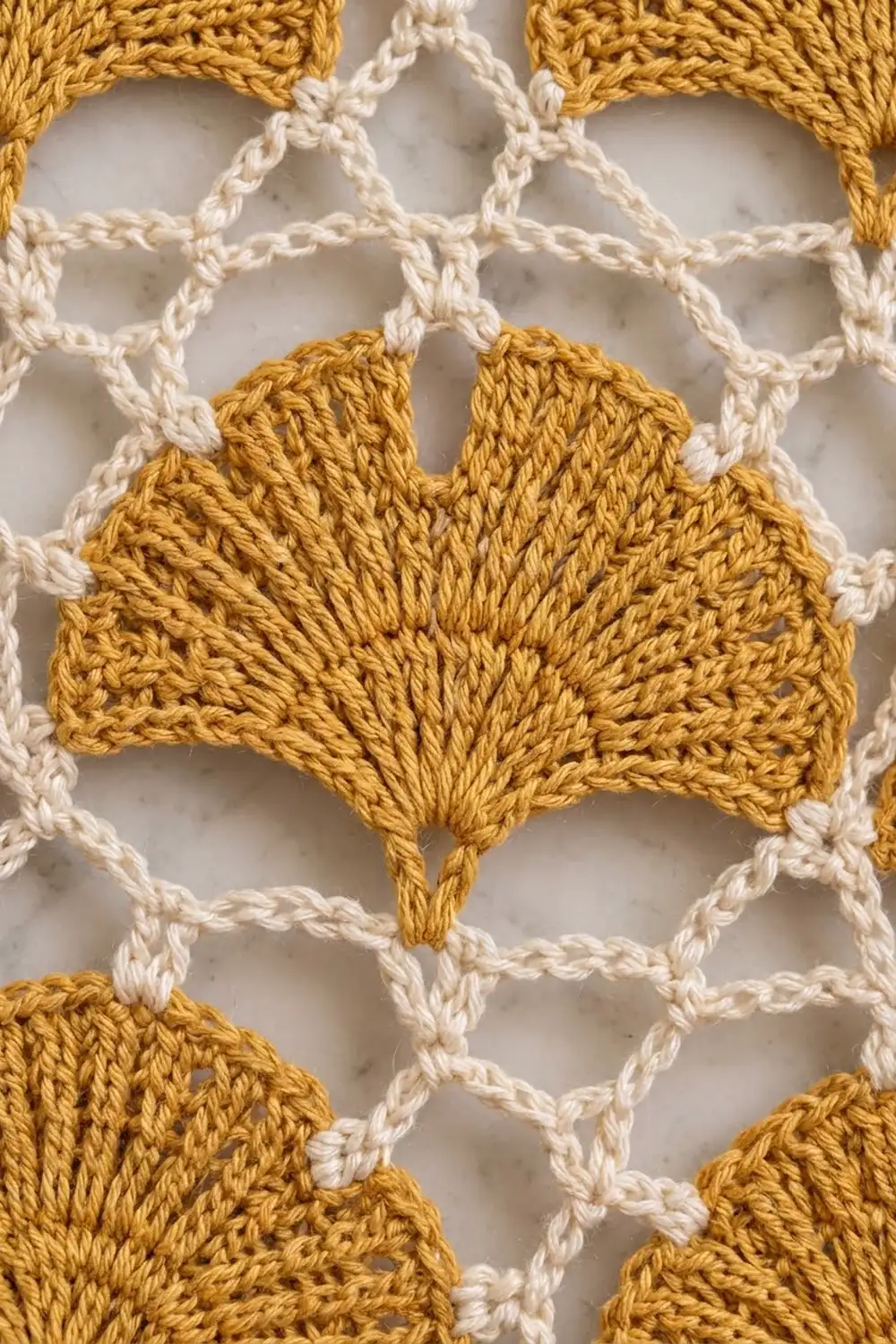 Mustard-gold crocheted leaf detail centered on cream chain-link mesh netting background.