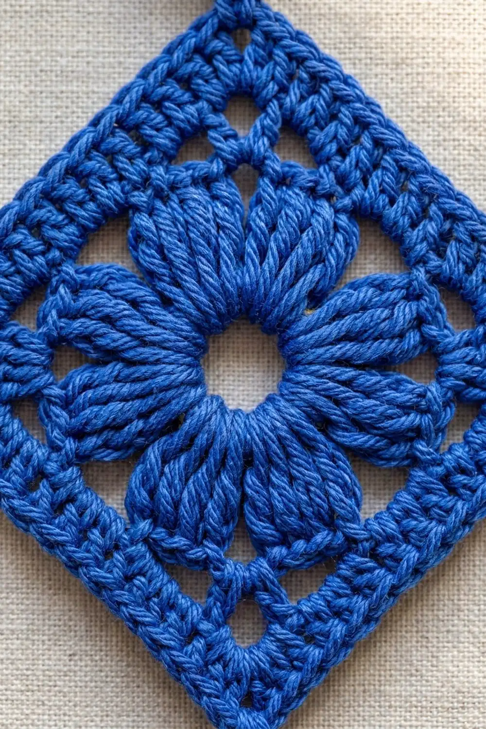 Bright blue crochet motif with geometric openwork and central star detail on linen.