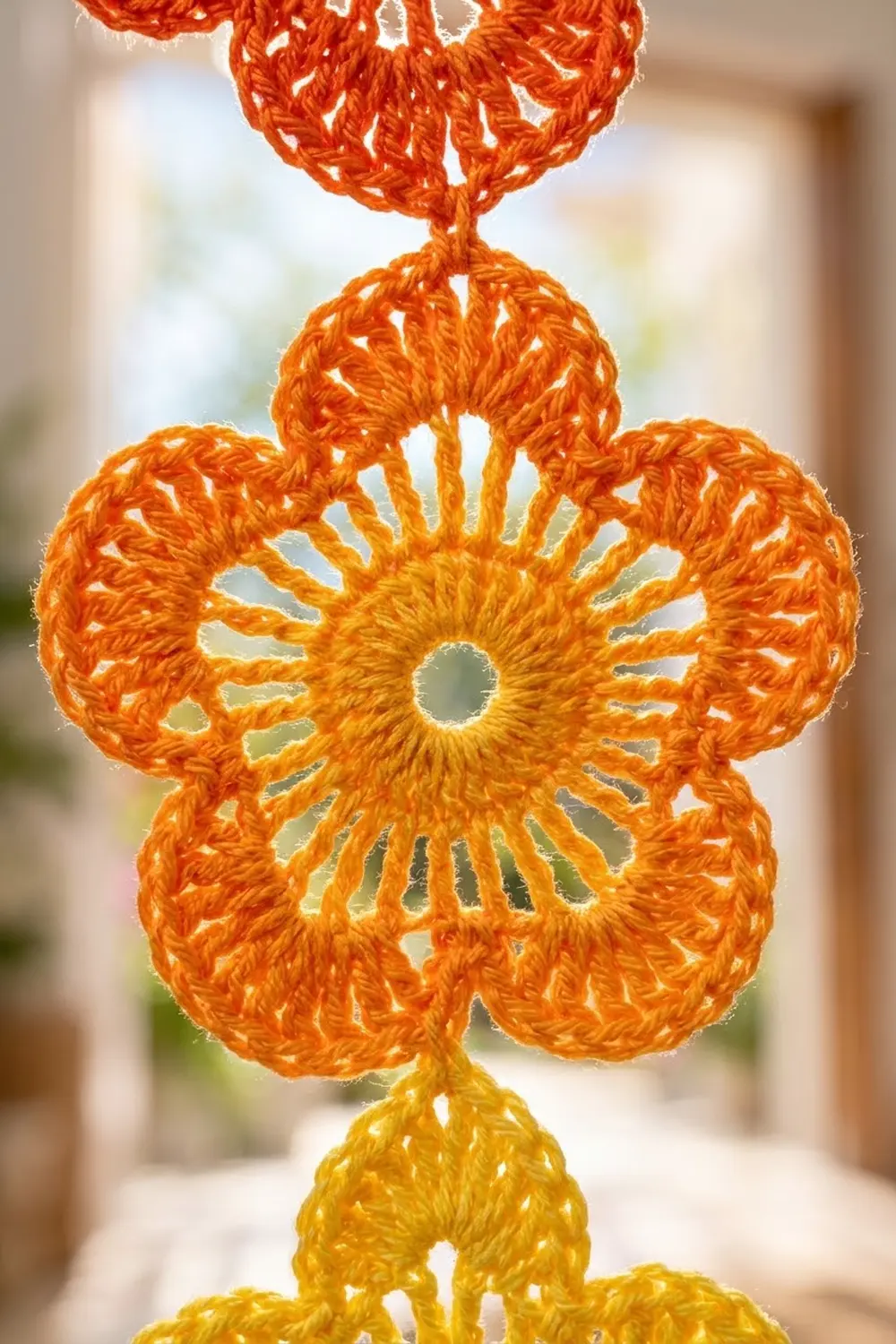 Stacked crocheted flowers with openwork petals in warm yellow and orange tones.