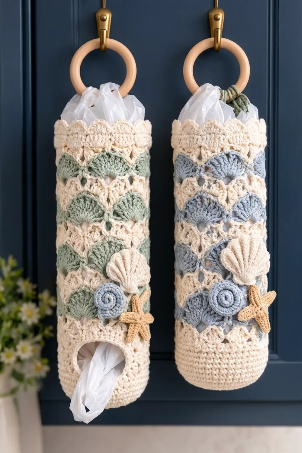 Cream crocheted tissue holders with blue and green accents and starfish details hanging from wooden rings on a dark wall.