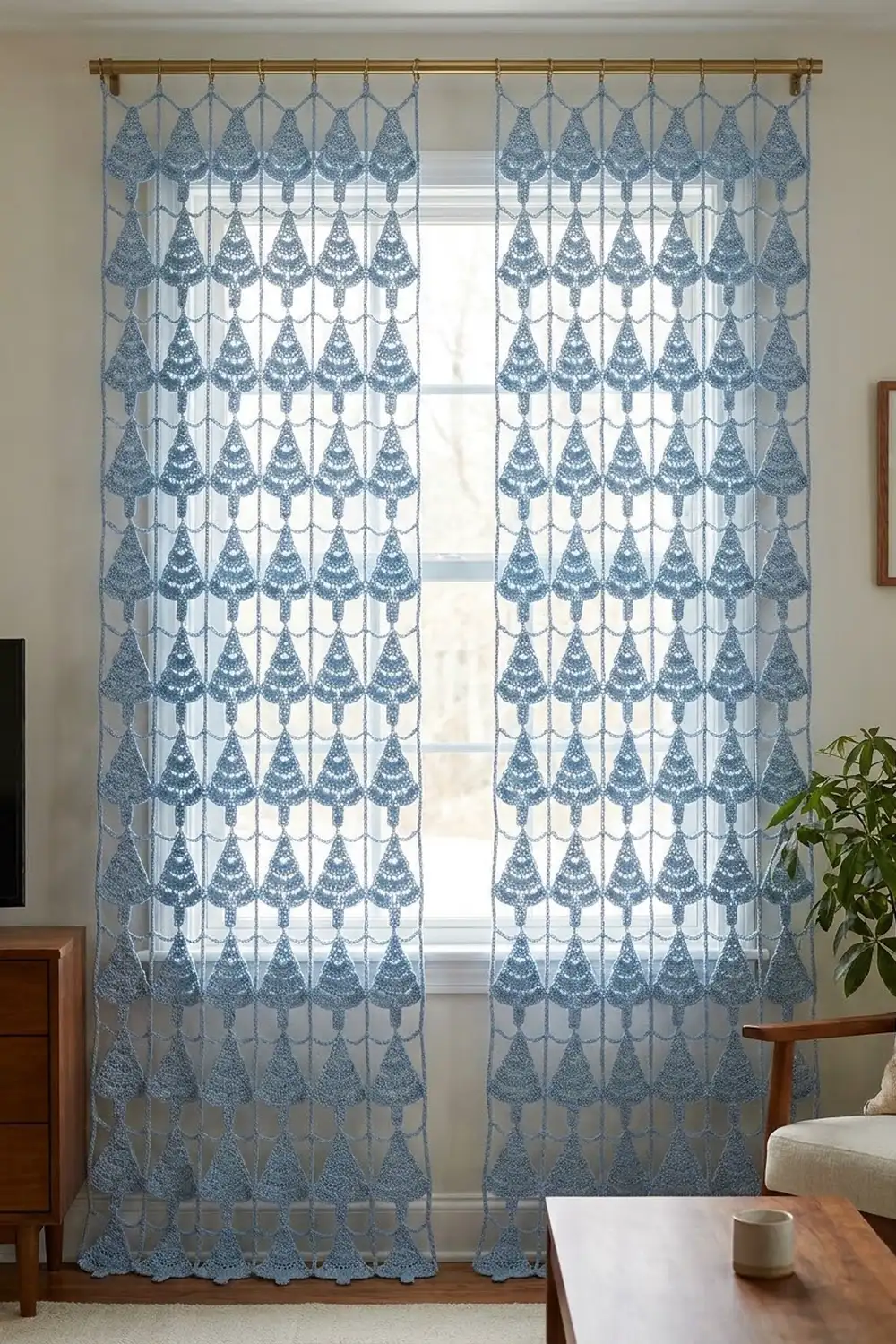 Sheer blue macramé curtains with lace leaf patterns frame a sunlit window in a minimalist living room.