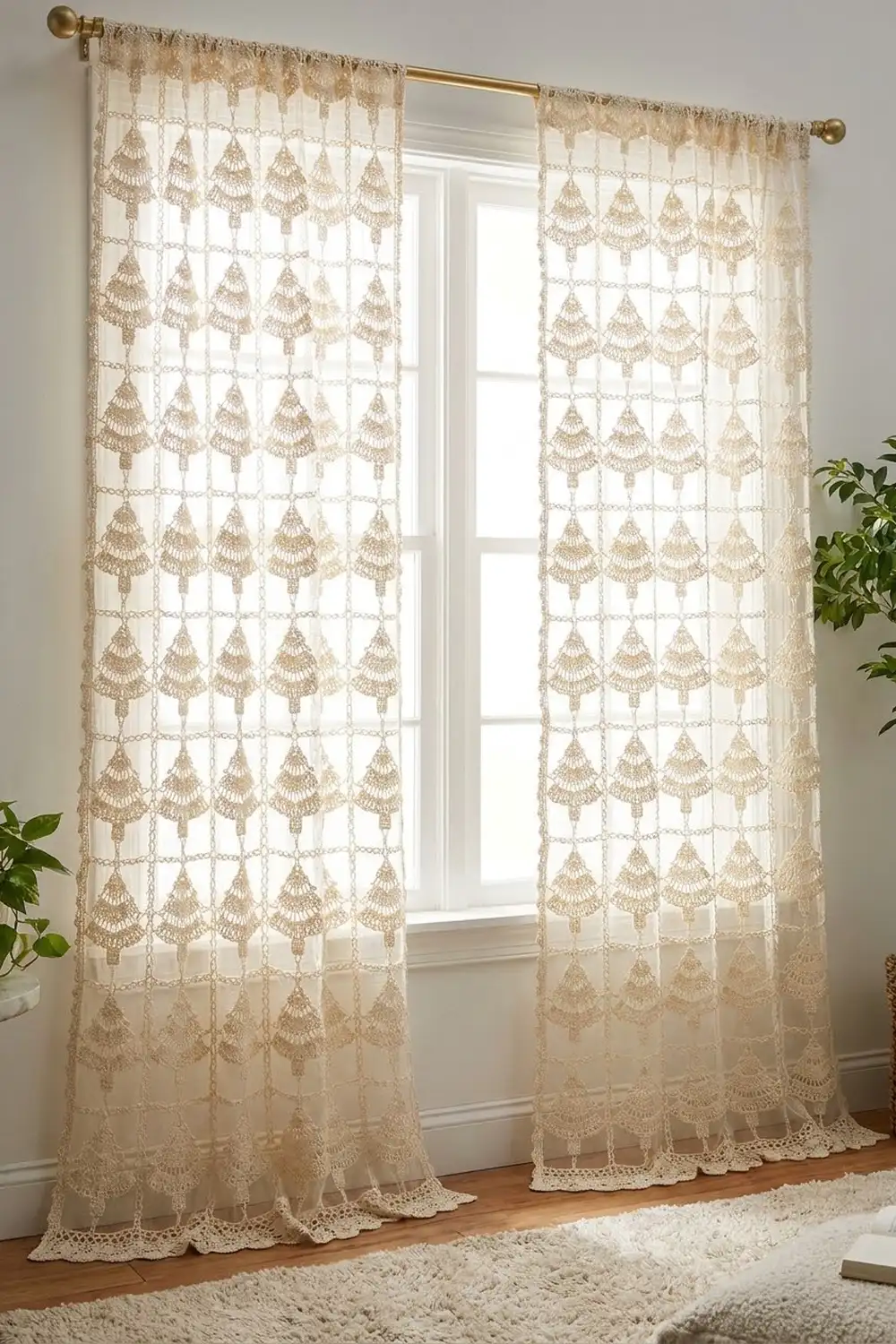 Cream lace crochet curtains with ornate tree design hang on brass rod before bright window with potted plants nearby.