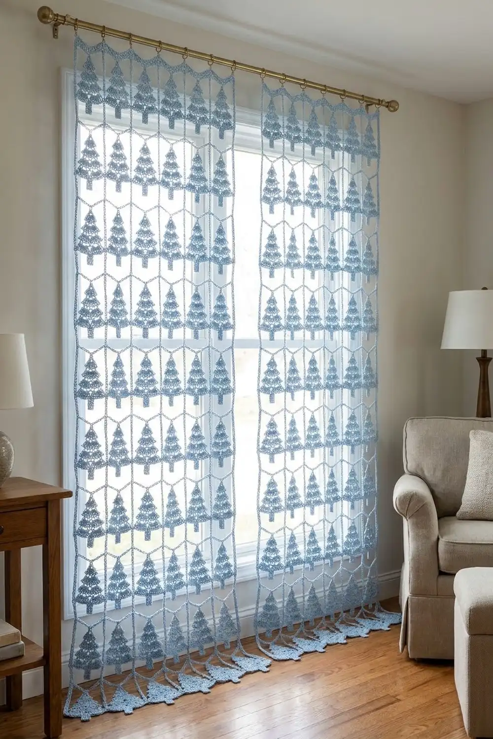 Sheer blue tree-patterned curtains with lace trim hang from a brass rod in a modern living room beside cream furniture.