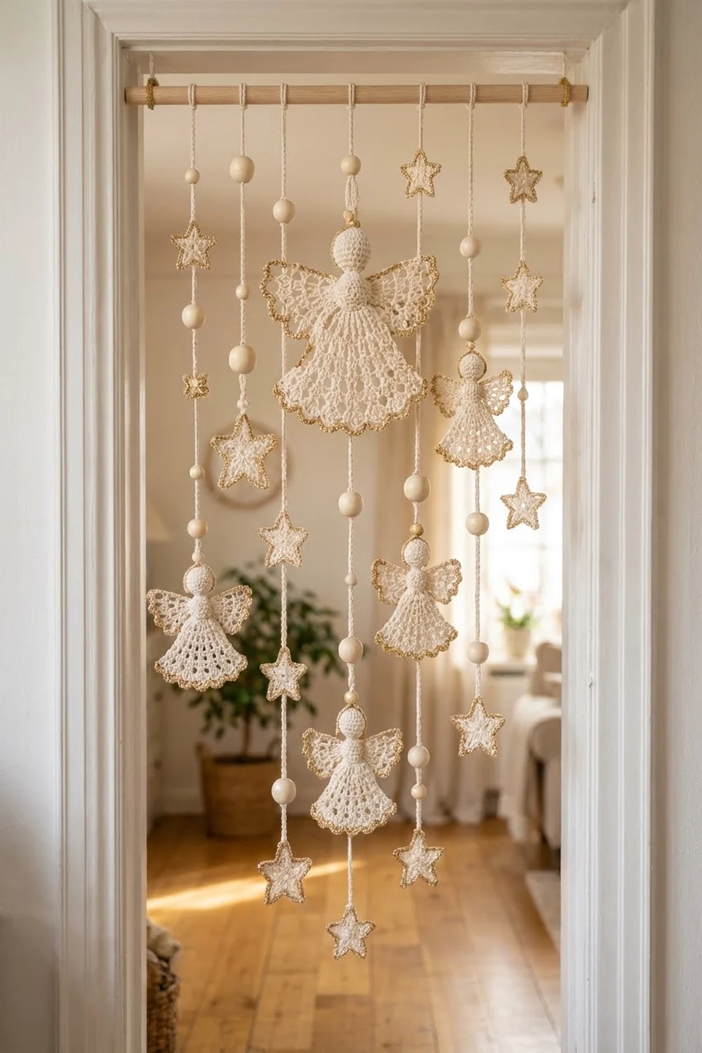 Cream-colored crocheted angels and stars hang from a wooden rod in a sunlit window, with beaded string accents.