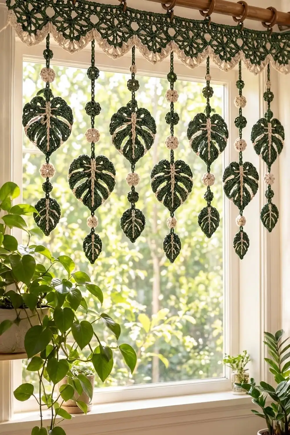 Dark green and cream crocheted leaf curtain hanging from a window rod, displayed with real potted plants on the sill.