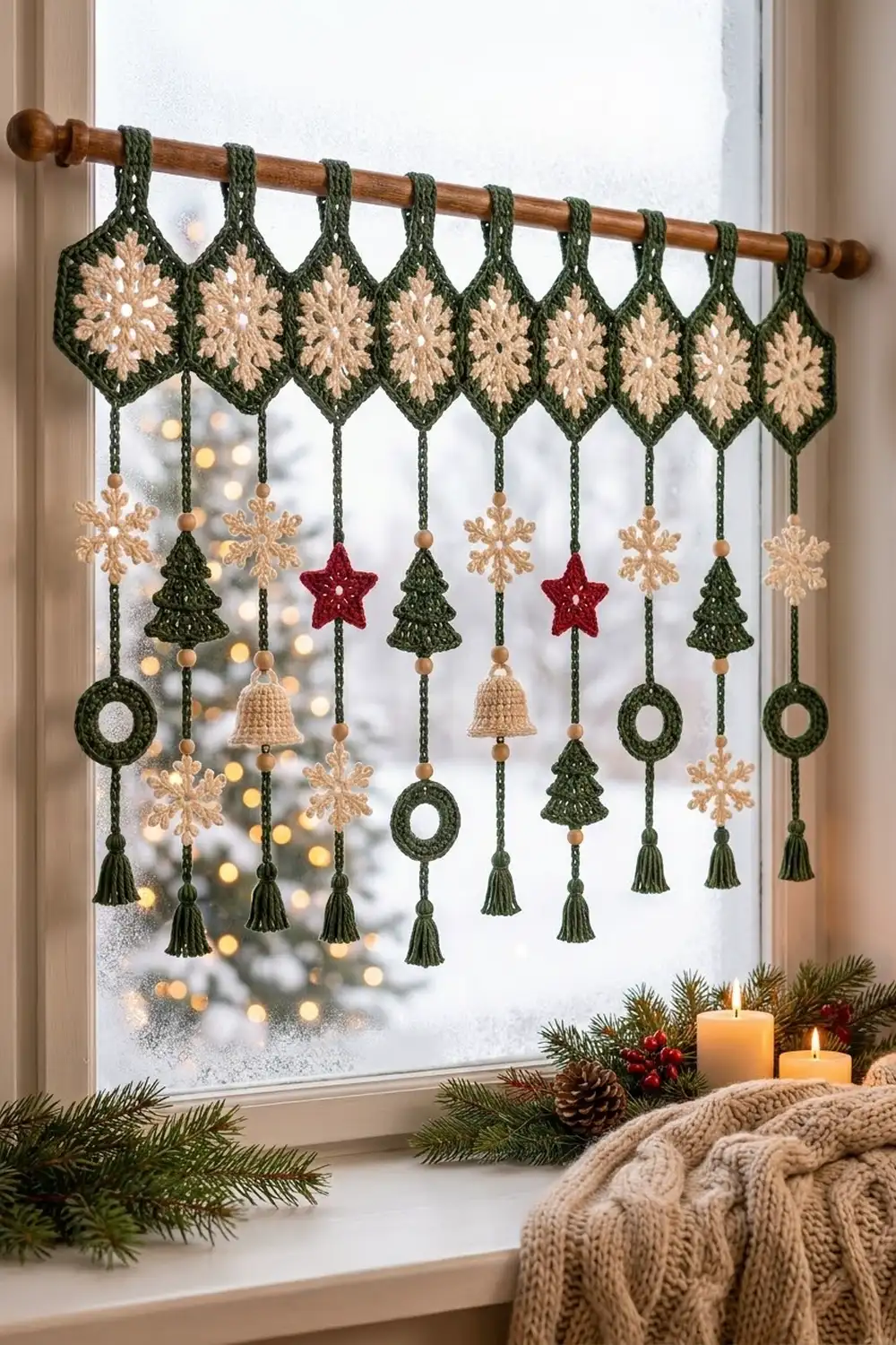 Crocheted green and cream holiday garland with ornaments hanging in a window above festive windowsill décor.