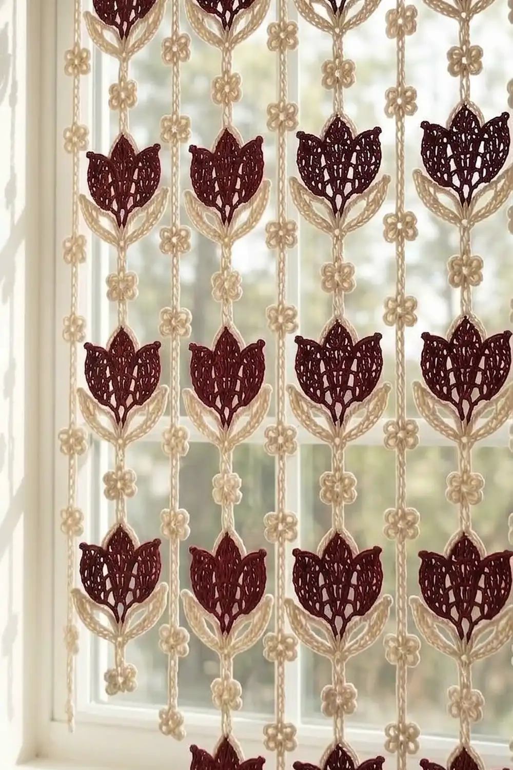 A beaded window curtain with burgundy tulips and cream flowers hanging in a bright window.