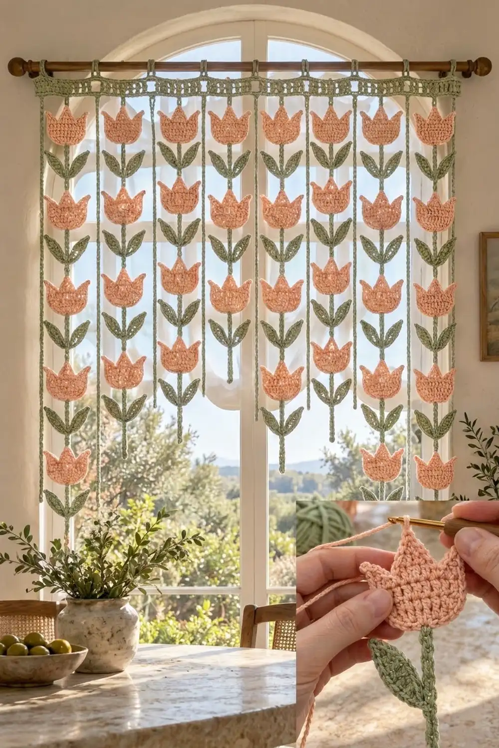 Crocheted coral tulip garland hanging on arched window above table with potted plant and bowl.