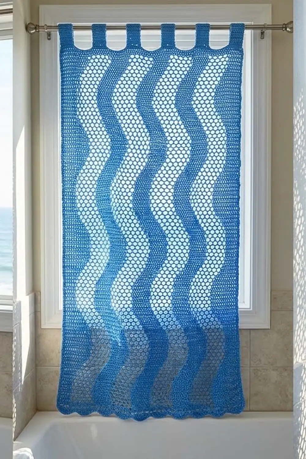A blue crocheted curtain with white diagonal stripe pattern hangs from a rod on a bathroom window.