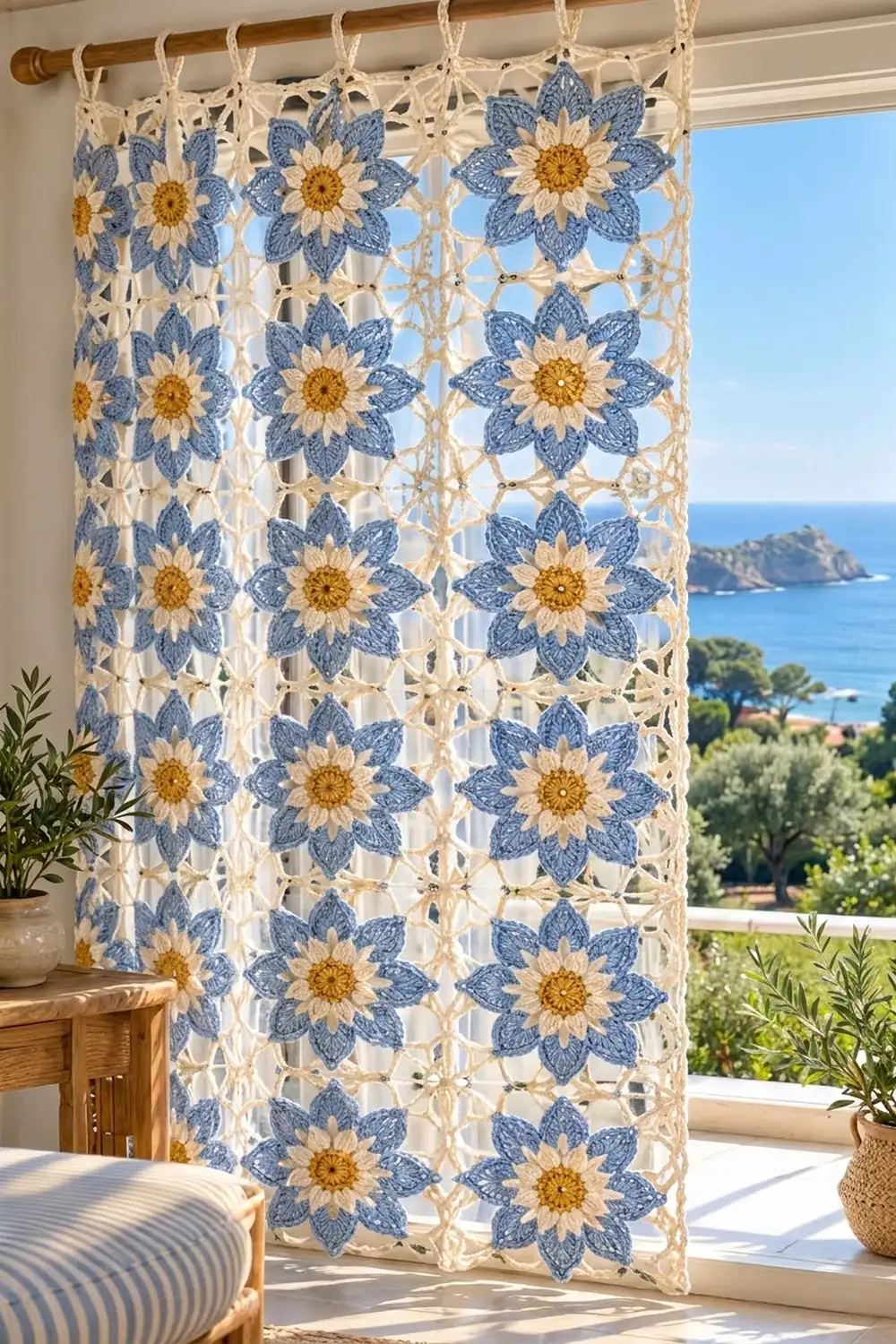 A crocheted curtain with blue and yellow flowers hangs in a sunny Mediterranean-style room overlooking the sea.