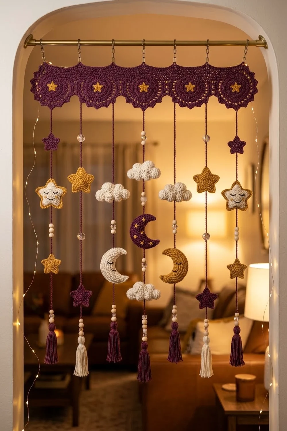 Purple crocheted mobile with hanging clouds, moons, and stars displayed in a warmly lit arched home nook.
