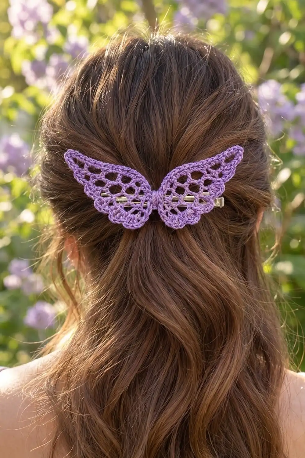 Purple crocheted butterfly clip adorning long brown hair against a blooming garden backdrop.