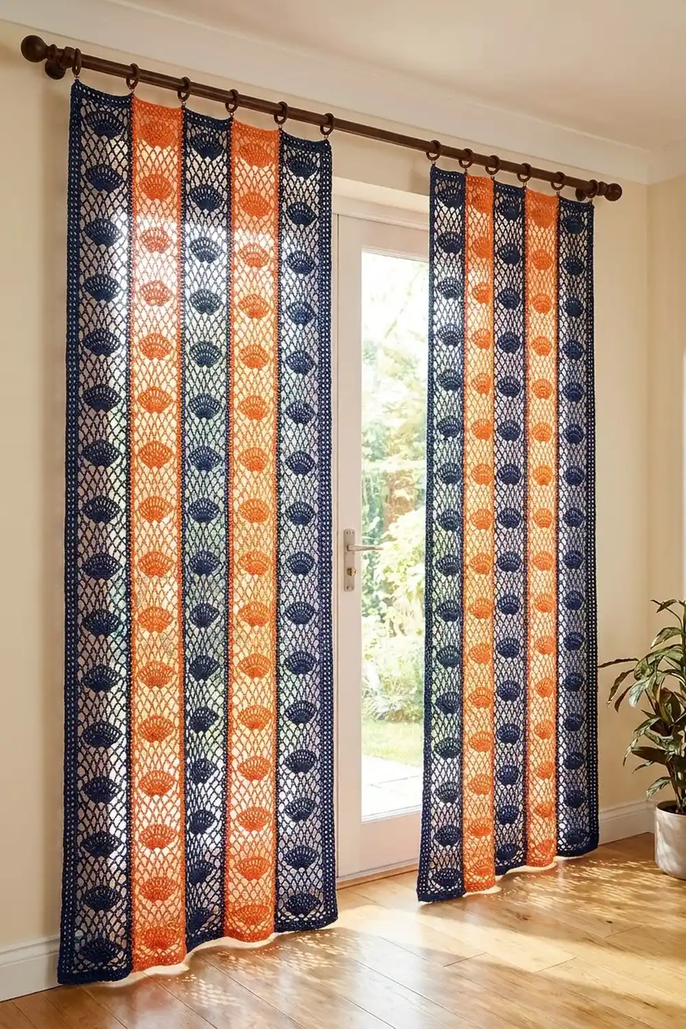 Navy and rust-colored crochet curtains with a delicate shell pattern frame a glass door in a bright, modern home interior.