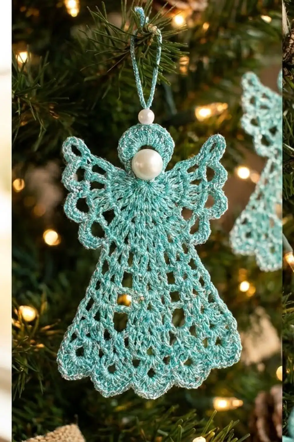 Turquoise crocheted angel ornament with lacy wings and pearl bead head hanging on a lit evergreen tree.