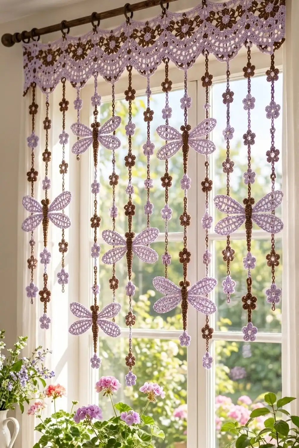 Crocheted lavender and bronze window valance with hanging lace dragonflies, displayed in a bright sunlit window above fresh flowers.